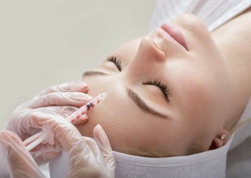 hands of cosmetologist making injection in face, lips. young woman gets beauty facial injections in salon. face aging, rejuvenation and  hydration procedures. aesthetic cosmetology. close up.