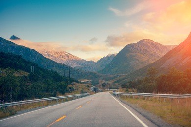 mountain road at sunset with blue light cloudy sky