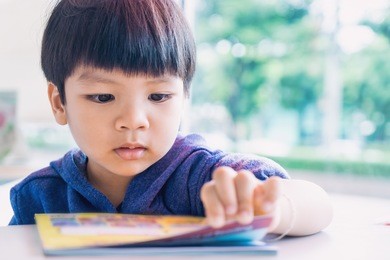 japanese boy is reading a educational play book.