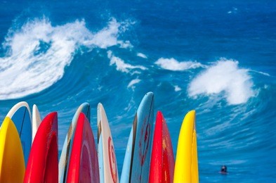 dramatic powerful waves break over beach with stack of surfboards ready to go on beach at lumaha'i, kauai, hawaii