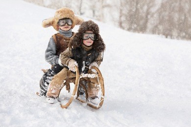 two boys sledding with mountain warm winter day
