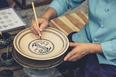 artist sketch drawing paint pattern in earthenware, making of handcraft pottery in sukhothai, thailand.