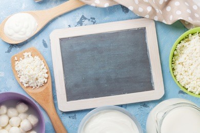 dairy products on stone table. sour cream, milk, cheese, yogurt and curd. top view with blackboard for your text