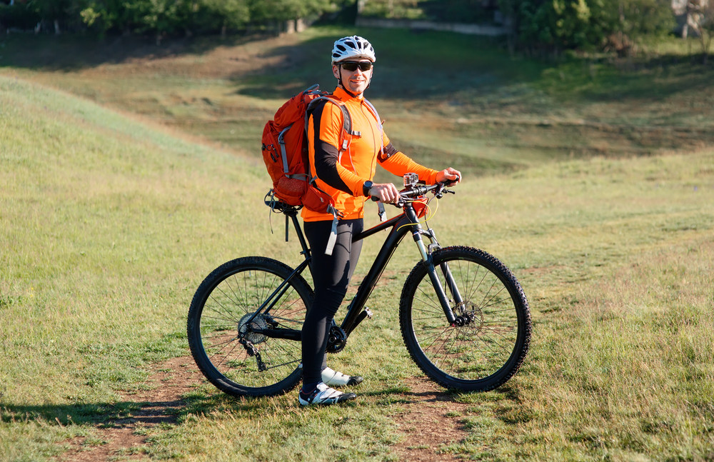 young man standing with bicycle on an countryside road