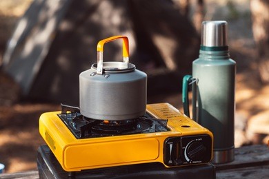 campfire kettle at campsite plate for cooking, making tea or coffee. outdoor food drink item set. travel tools, camping explorer equipment. nature picnic rest. thermos with hot beverage.