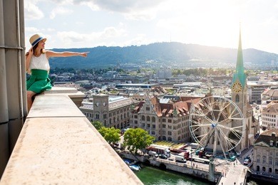 top view on zurich city with young woman showing sitting on the tower's top. woman having a great vacation in switzerland