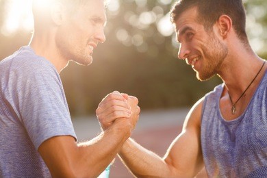 two hot men shake each others hands on summer day