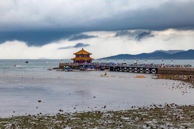 zhanqiao pier under a stormy sky in summer, qingdao, shandong, china. zhanqiao is the famous pavilion displayed on the bottles of qingdao beer
