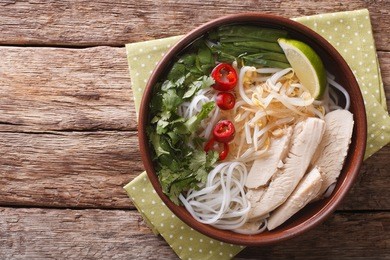 vietnamese soup pho ga with chicken and rice noodles, bean sprouts and chilli in a bowl close-up. horizontal view from above