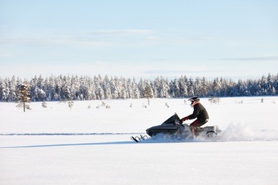 man driving sports snowmobile in finnish lapland in a sunny day