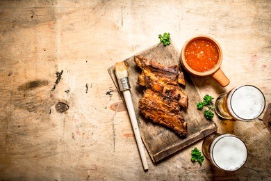 smoked barbecue ribs with tomato sauce and cold beer. on wooden background.
