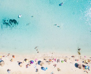 aerial view of sandy beach with tourists swimming in beautiful clear sea water