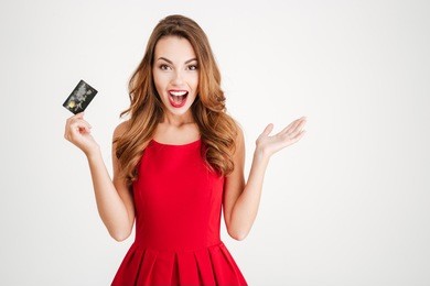 cheerful excited surprised young woman with credit card over white background
