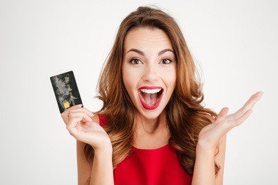 happy excited amazed young woman holding credit card over white background