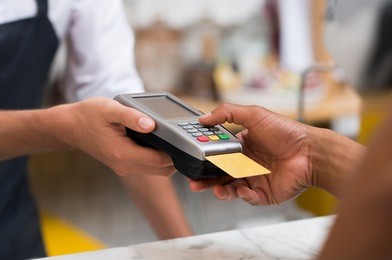 close up of hand using credit card swiping machine to pay. hand with creditcard swipe through terminal for payment in cafeteria. man entering credit card code in swipe machine.