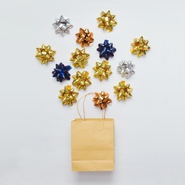 christmas shopping bag with bows and stars on white background. flat lay.