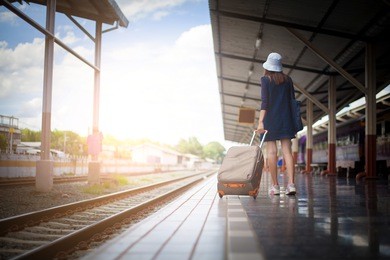 a young girl walking alone carrying luggage and waits train on railway station