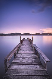 wooden pier or jetty on blue lake sunset and sky reflection water. long exposure, versilia massaciuccoli, tuscany, italy.
