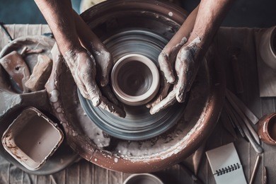 making it together. top view of potter teaching child to make ceramic pot on the pottery wheel