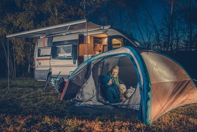 caucasian family camping fun. caucasian family in the tent. rv motorhome camper in the background.