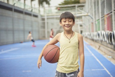 asian boy standing at basketball court smiling