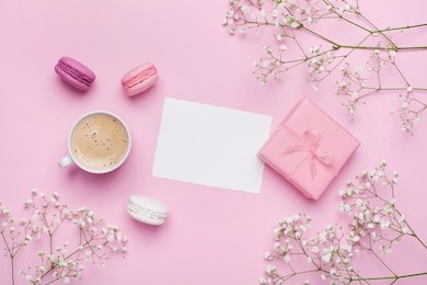 morning cup of coffee, cake macaron, gift or present box and flower on pink table from above. beautiful breakfast. flat lay style.