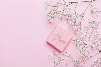 gift or present box and flower on pink table from above. pastel color. greeting card. flat lay style.
