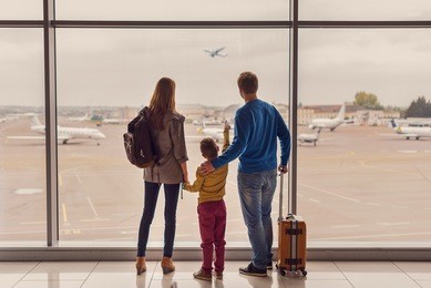 such large aircraft. back view shot of young family with luggage standing near window in airport before boarding