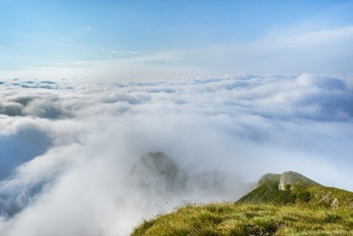 picturesque view of a layer of white clouds below the mountain peaks in the bucegi mountains from the carpathians in romania. mountain scenic landscape above the clouds. 