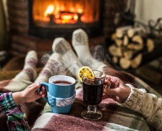 warming and relaxing near fireplace. woman feet near the cup of hot drink in front of fire.  