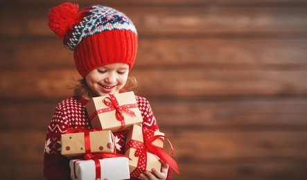 happy child girl with a christmas present on wooden background