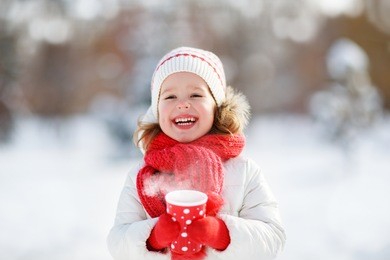 happy child girl with a cup of hot tea in winter  walk outdoors