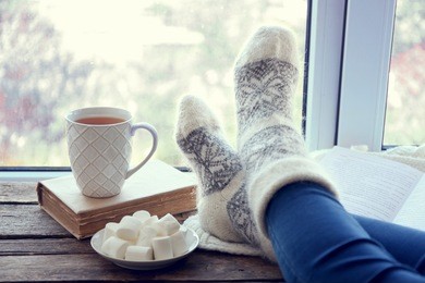 female legs and hot drink with marshmallows on windowsill