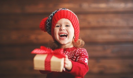 happy child girl with a christmas present on wooden background