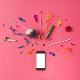 smartphone with colorful party items on pink background. flat lay.