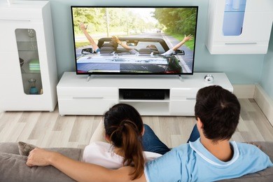 young couple on sofa watching movie on television together at home