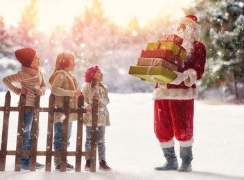 merry christmas and happy holiday! cute children girls and boy playing on a winter walk in nature. happy kids outdoors. santa claus presents gifts to nice kids.