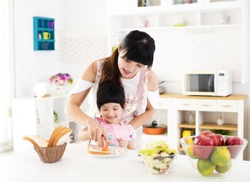 little girl helping her mother prepare food in the kitchen
