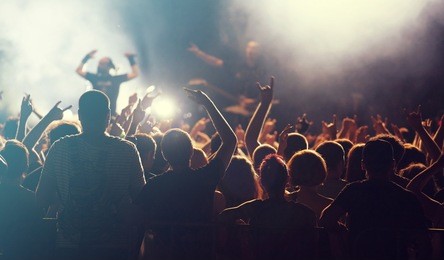 rock concert, cheering crowd in front of bright colorful stage lights