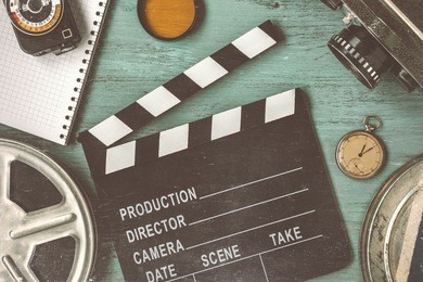 clapperboard and a film reel, a stop watch, a notebook and a lens on the table