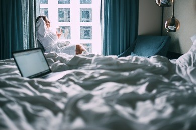 woman sits with cup of tea in hotel room at the rain morning