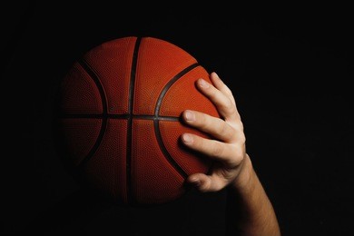 basketball ball in male hands on dark background