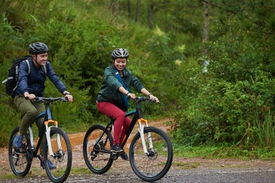 sporty asian couple riding bicycles in forest