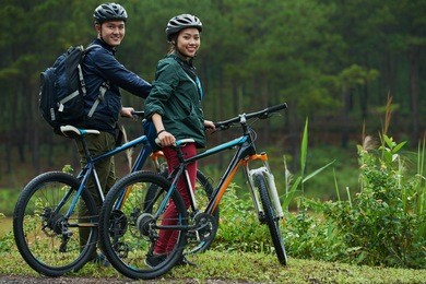 vietnamese happy couple with bicycles standing in forest