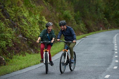 happy excited couple riding bicycles along the road