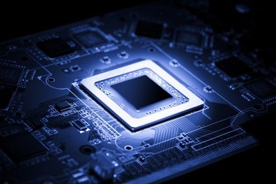 glowing modern processor. big illuminated graphic processor surrounding by other electrical components. special tone image. low aperture shot, focus on lower part of chip.