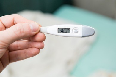 male hands holding a digital thermometer with high temperature