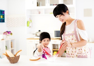 little girl helping her mother prepare food in the kitchen