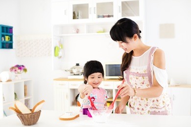 little girl helping her mother prepare food in the kitchen