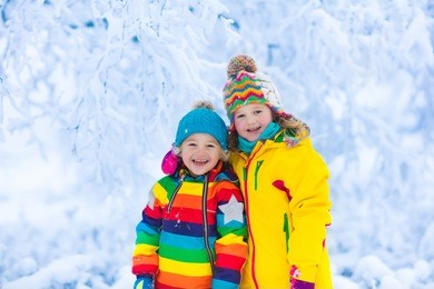 children play in snowy forest. toddler kids outdoors in winter. friends playing in snow. christmas vacation for family with young children. little girl and boy in colorful jacket and knitted hat.